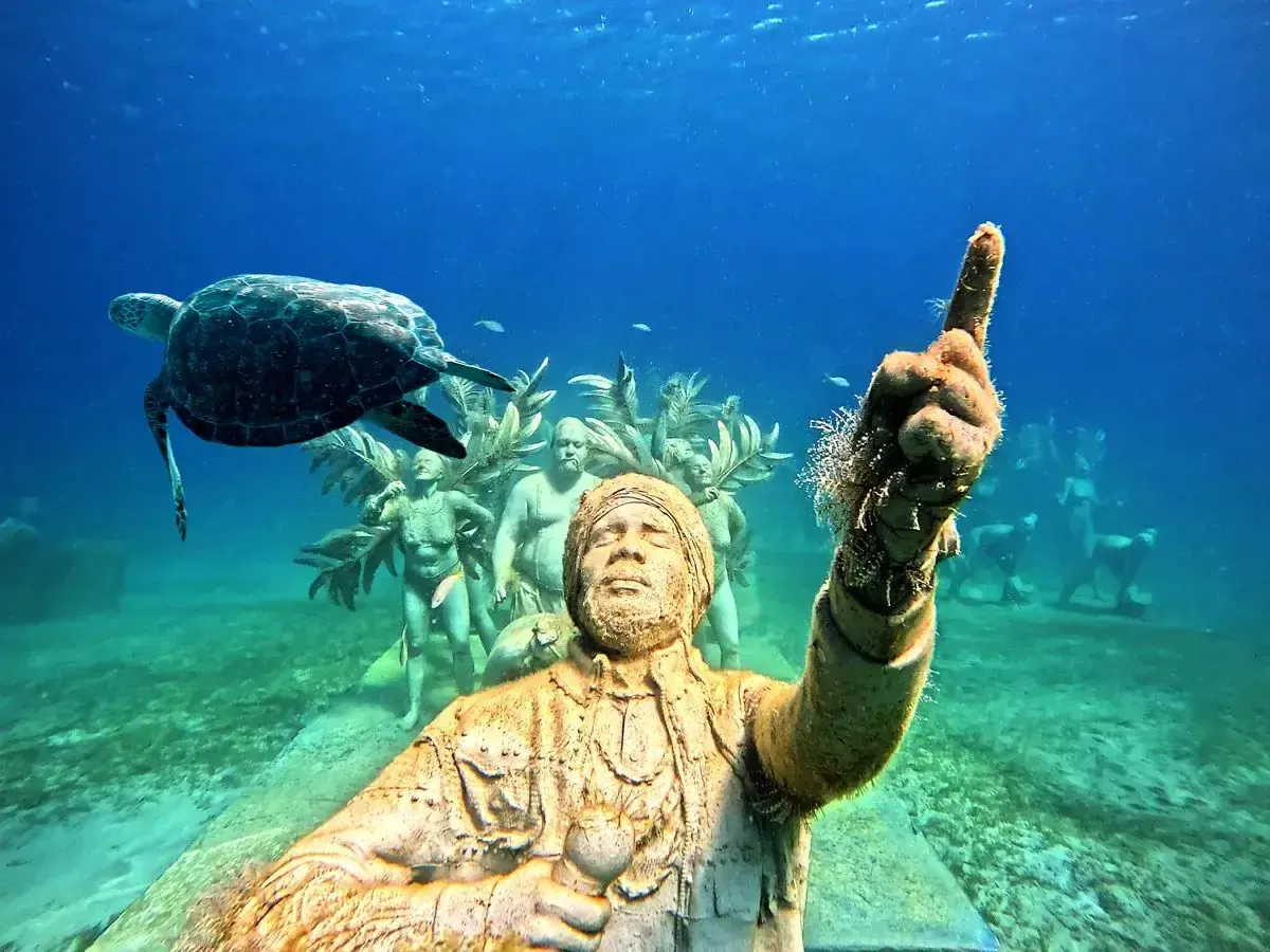 Tortue nageant au-dessus d'une sculpture sous-marine a Under SXM