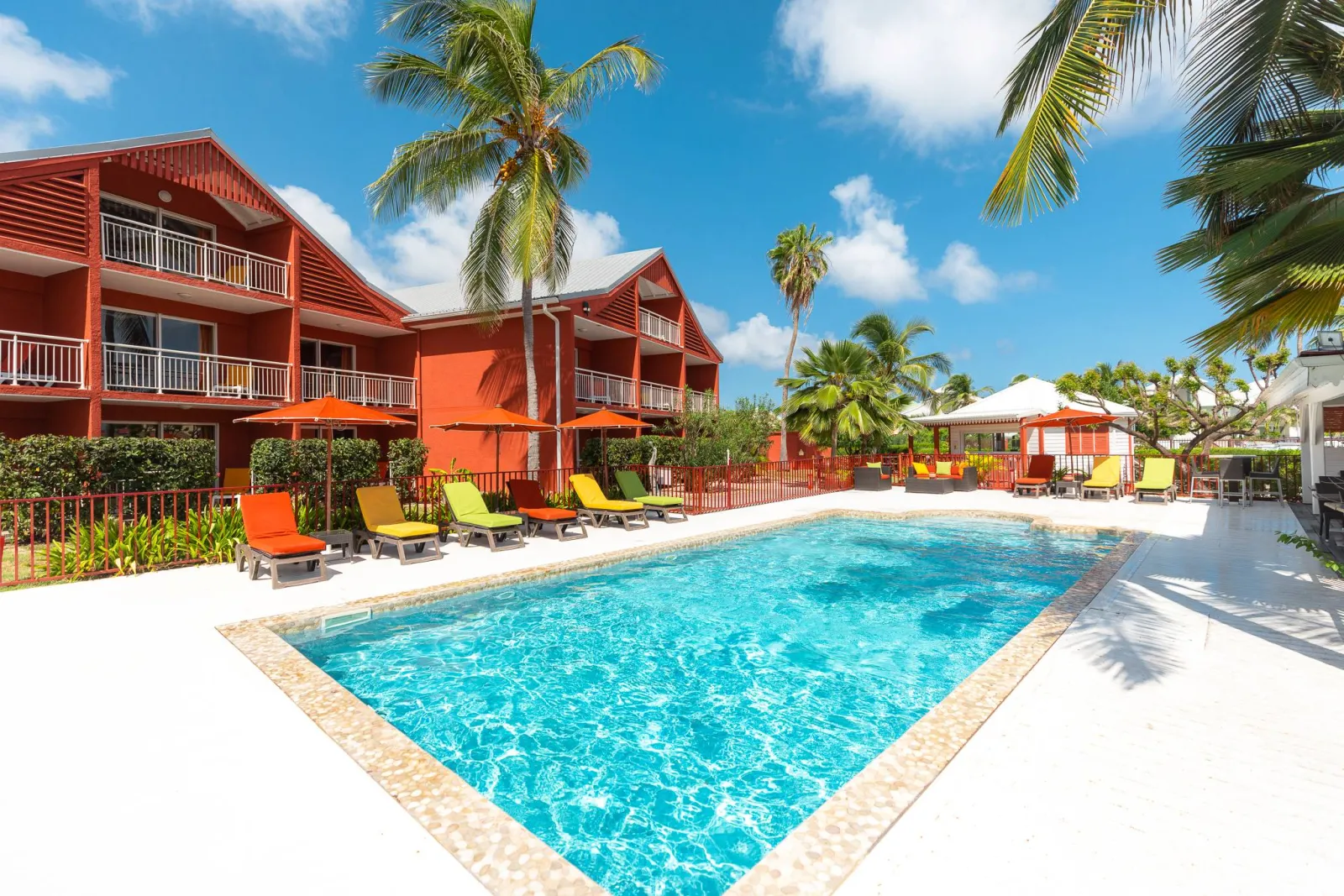 Piscine et batiments rouges de Palm Court Residence