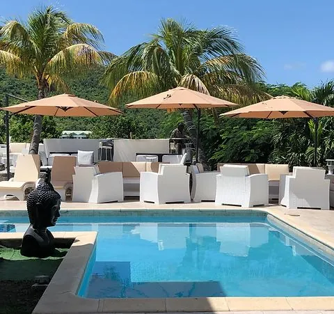 Piscine et lounge de jour à 978 Sanctorum avec parasols beiges, palmiers et statue Bouddha