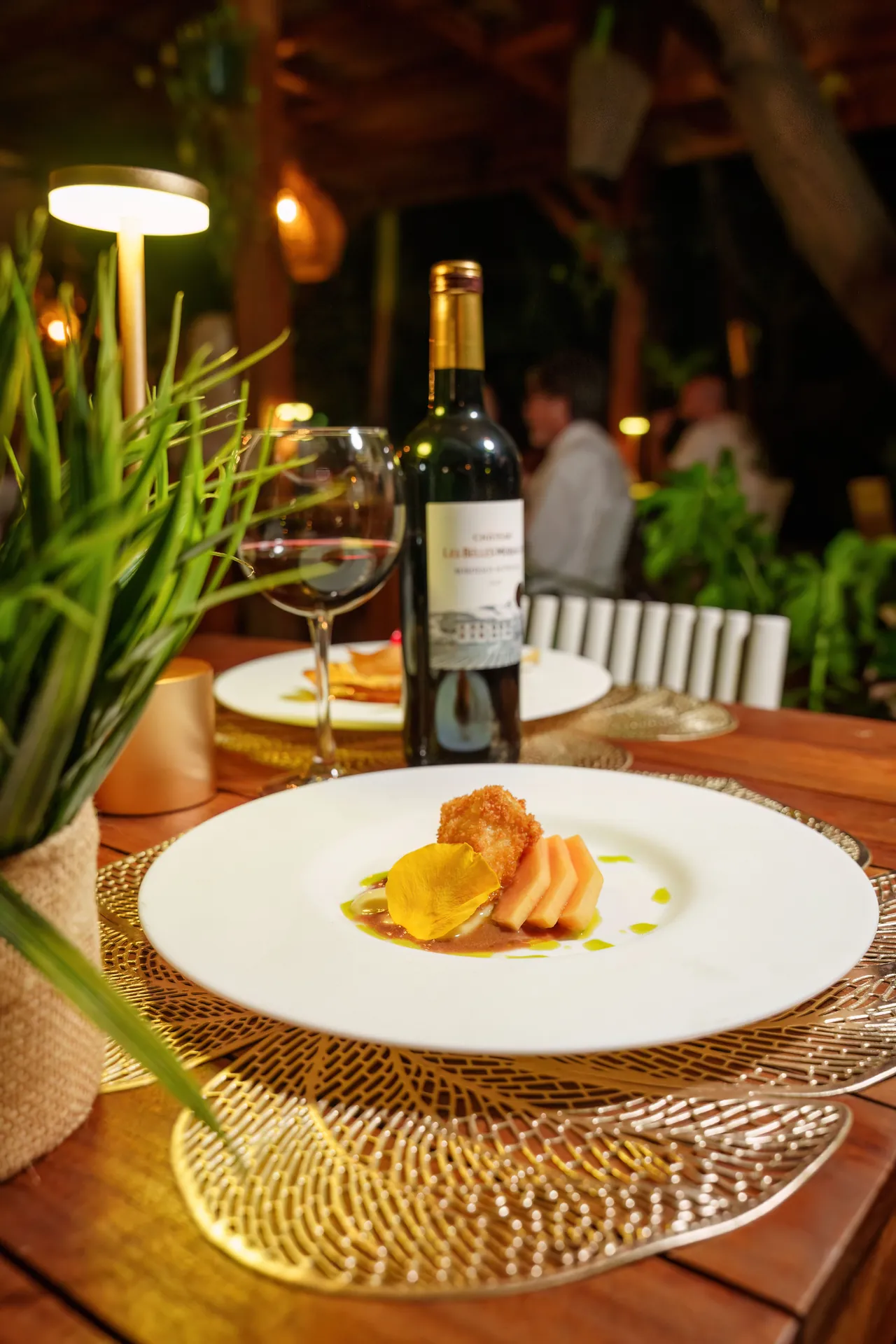 Plat créole gastronomique de 978 Sanctorum servi avec une bouteille de vin rouge