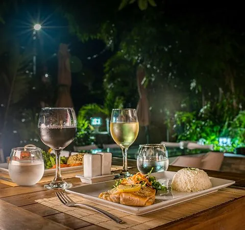 Poisson grillé au riz et verres de vin sur table en bois dans le jardin de 978 Sanctorum