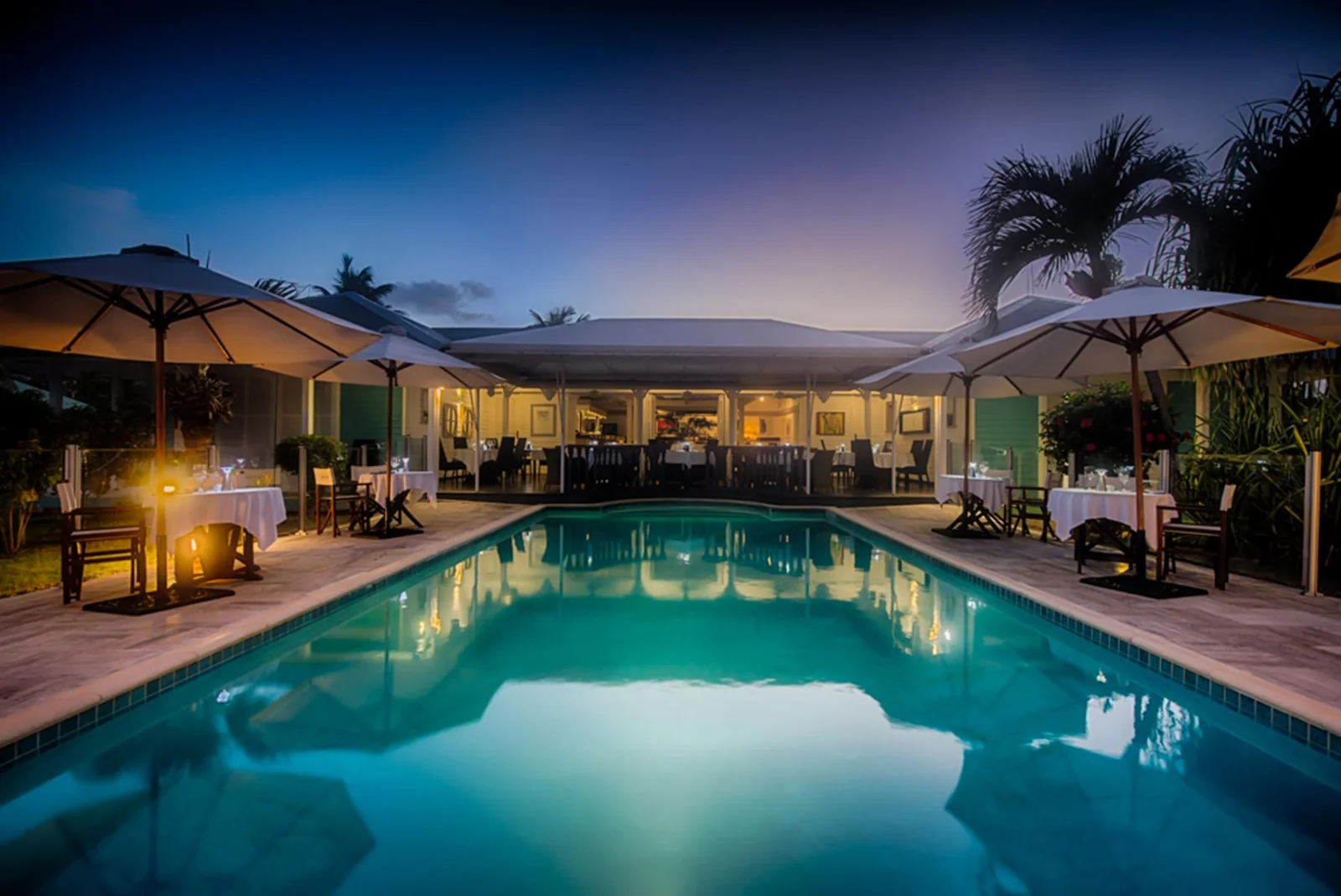 L'Astrolabe au crépuscule : piscine éclairée et tables nappées blanches autour du restaurant à l'Esmeralda Resort