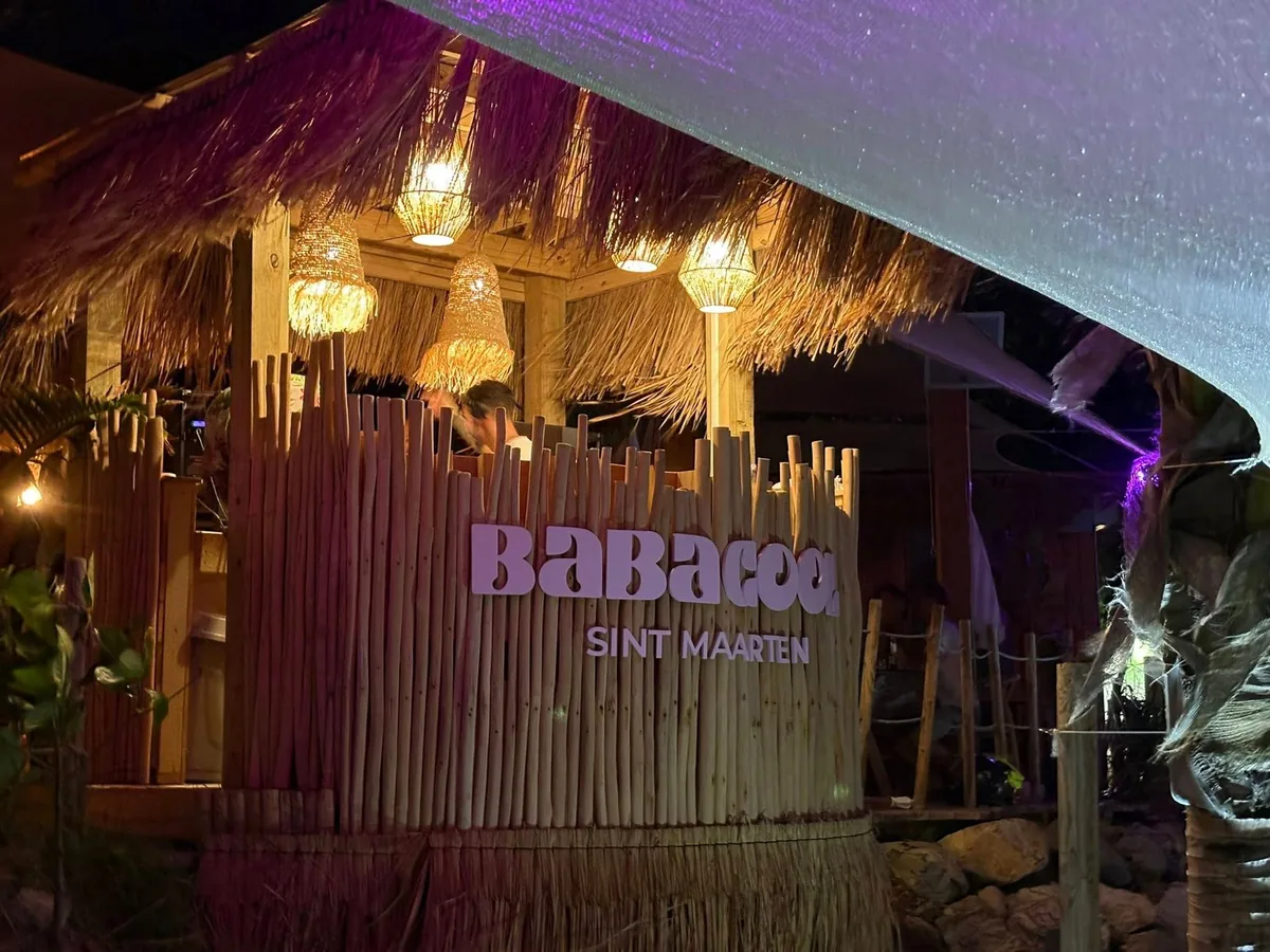 Salle bois et bambou de Babacool avec banquettes rayées rose et tables face à la plage