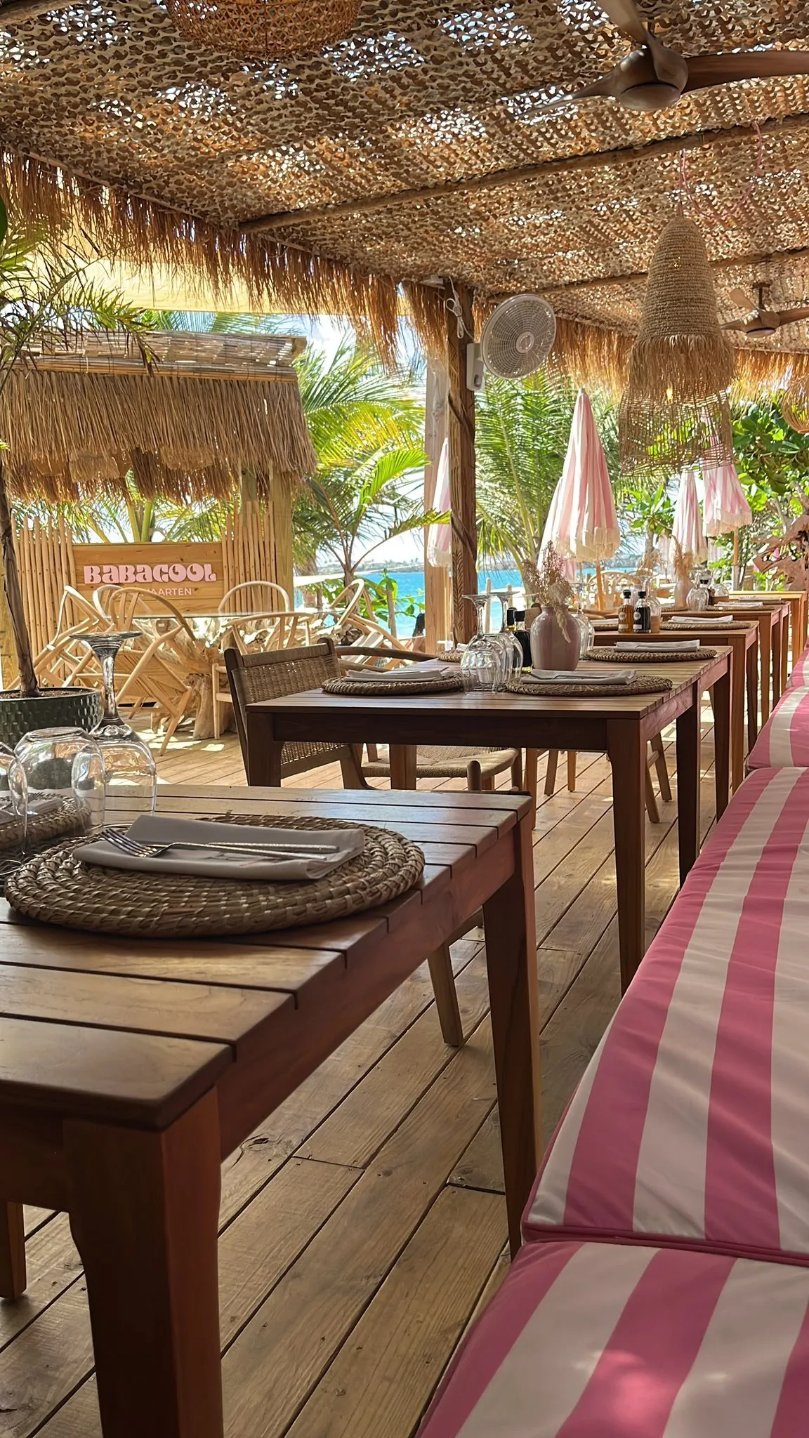 Restaurant Babacool en journée : tables en bois sous toiture en chaume et fronton BABACOOL en arrière-plan