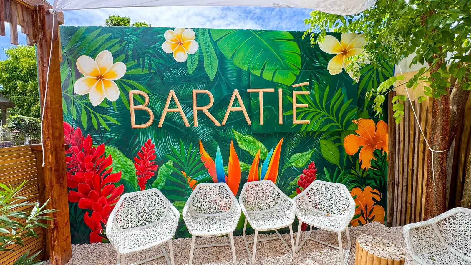 Baratié SXM à Marigot : entrée avec grande fresque tropicale BARATIÉ et chaises en rotin