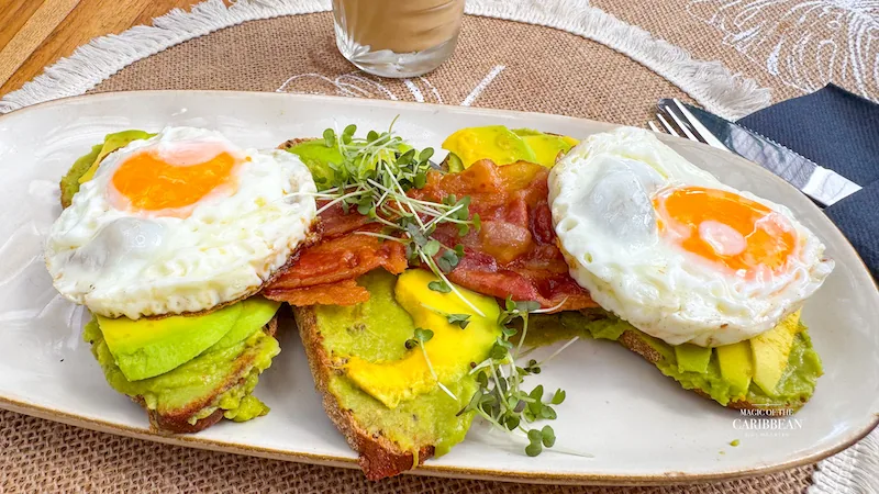Avocado toast aux œufs au plat et bacon servi au brunch de Baratié SXM