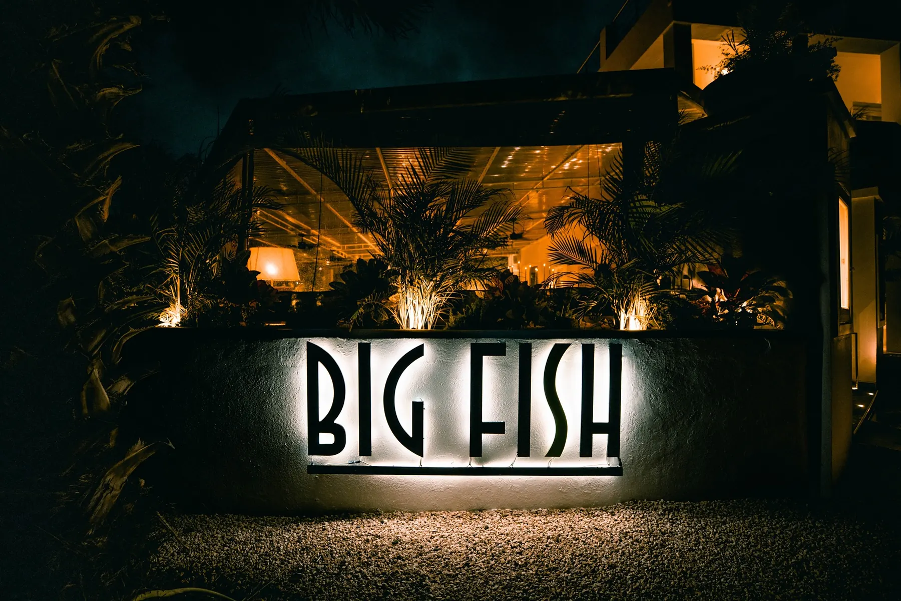 Big Fish Seafood Grill - enseigne lumineuse et entrée du restaurant de nuit à Oyster Pond