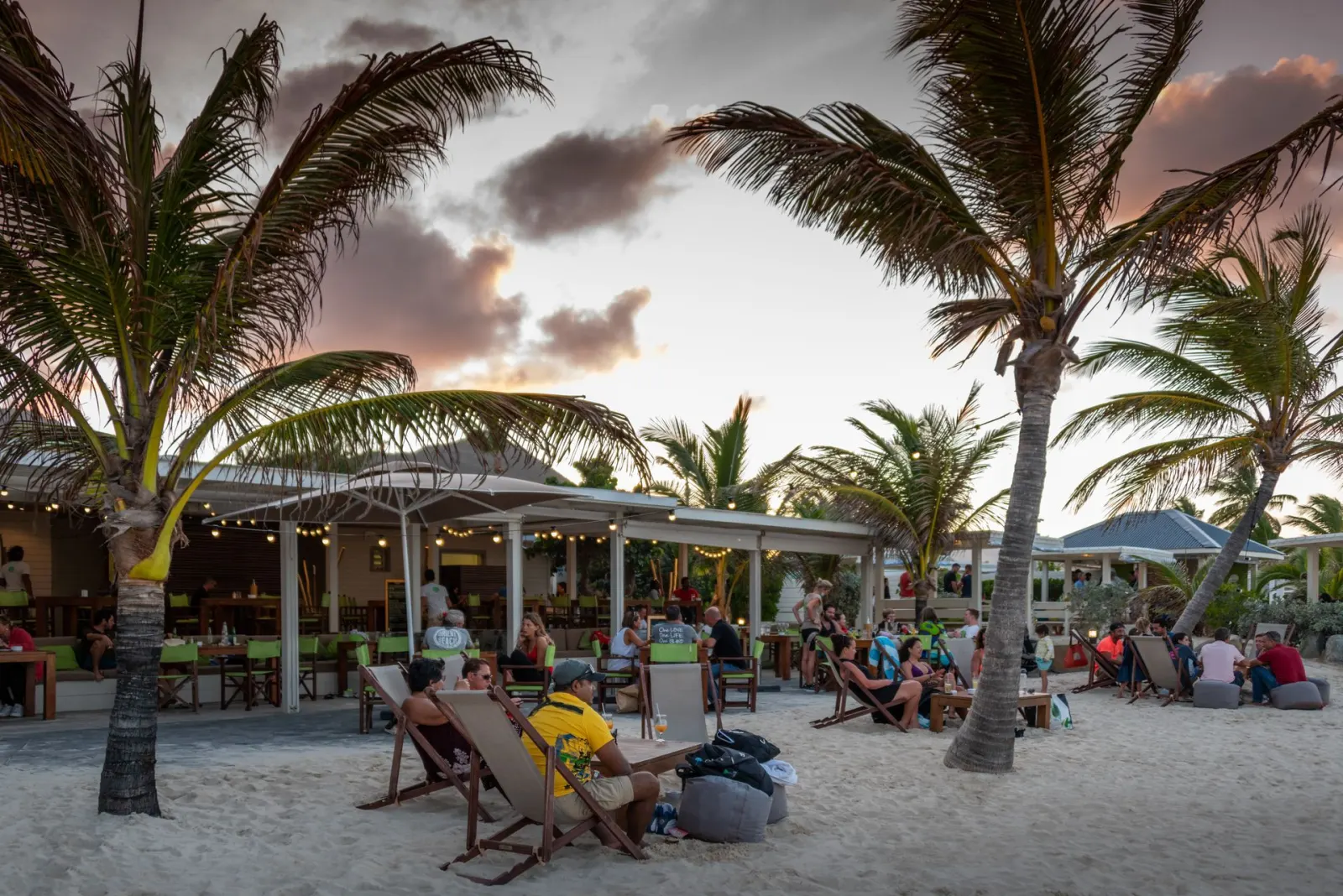 Bikini Beach à la Baie Orientale - terrasse de plage avec palmiers et coucher de soleil sur Orient Bay