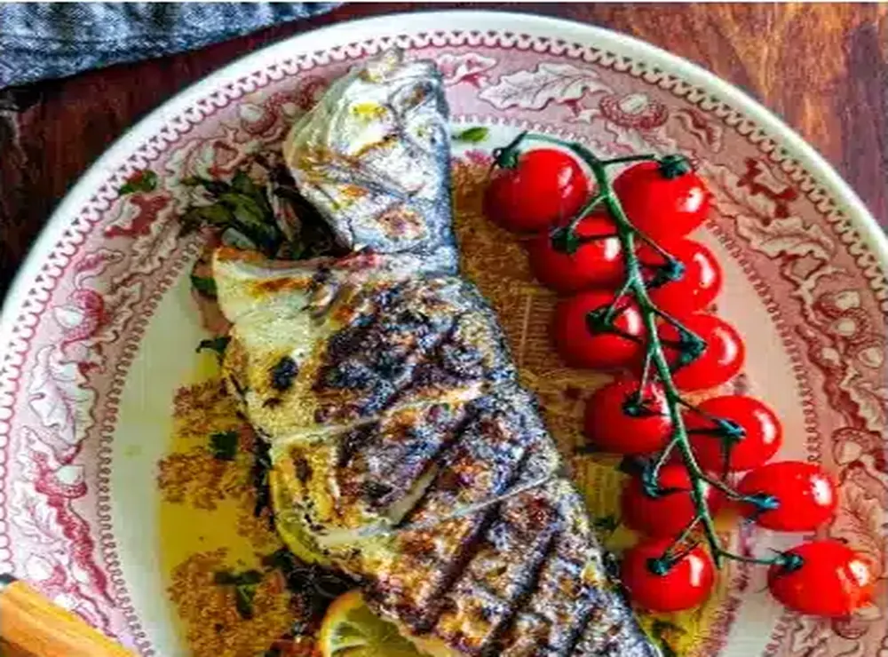 Poisson grillé avec tomates rôties dans l'assiette de Kalos