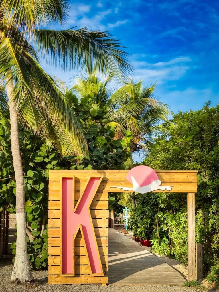 Karakter à Simpson Bay - entrée du beach club avec lettre K rose et palmiers