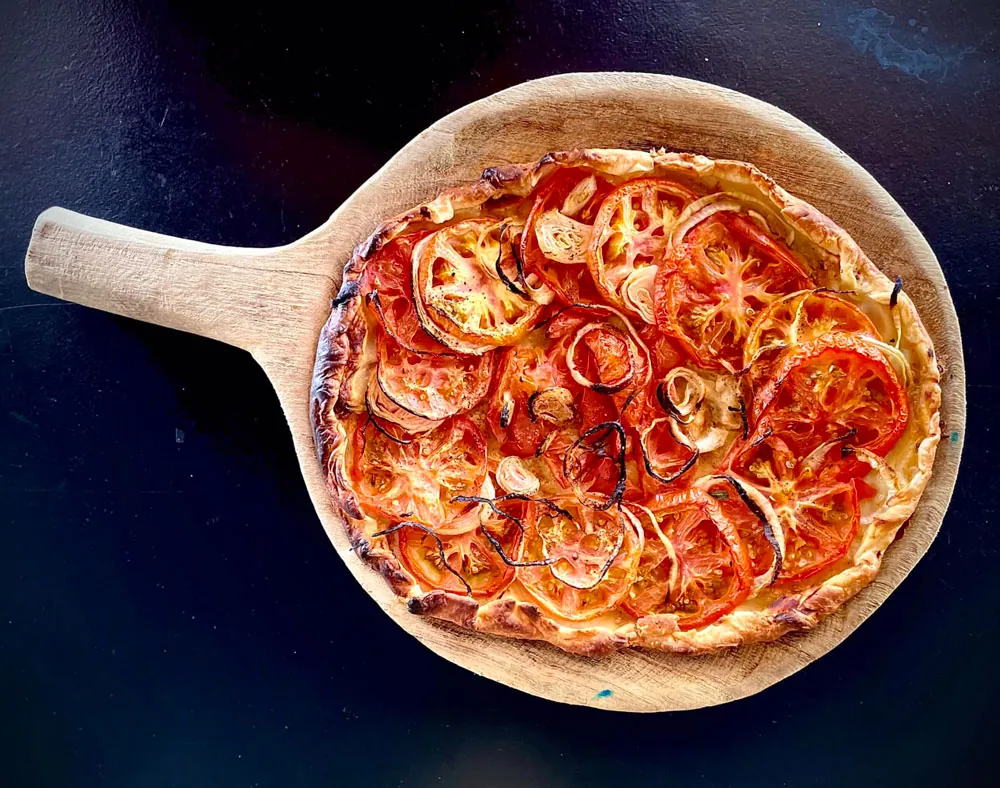 Tarte fine à la tomate et à l'oignon servie sur planche en bois à Korner SXM