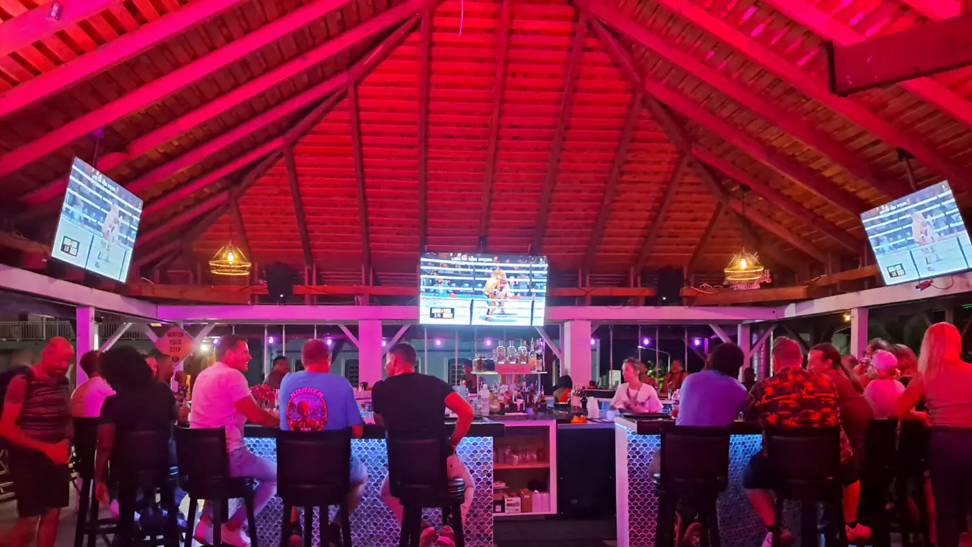 Kraken Raw Bar SXM - bar central avec ecrans sport et ambiance neon rose