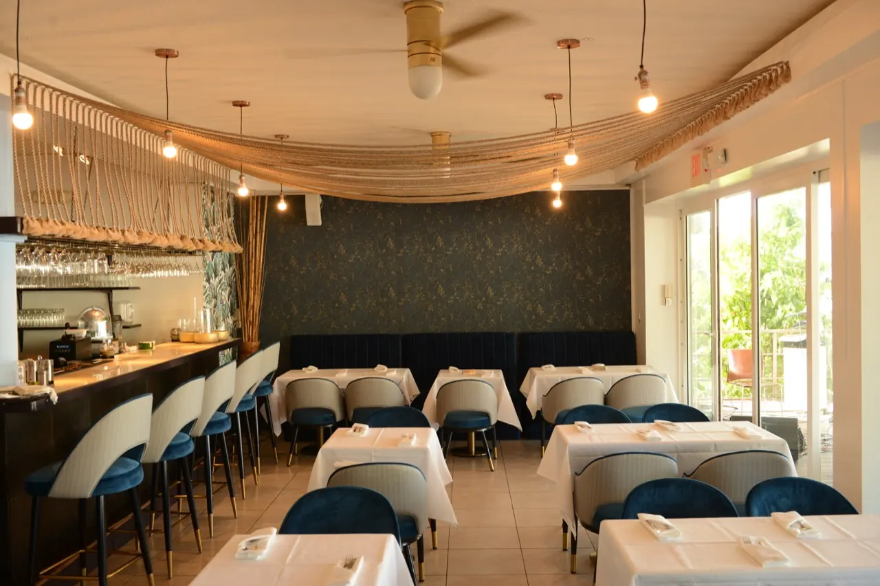 Salle intérieure de La Perle Bleu avec tables dressées, bar et décor blanc et bleu