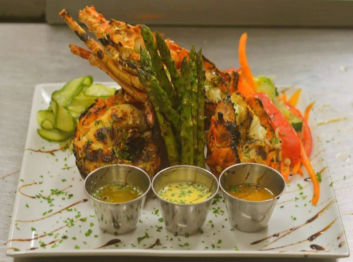 Plat de poisson et lobster servi avec légumes et sauces maison à La Perle Bleu