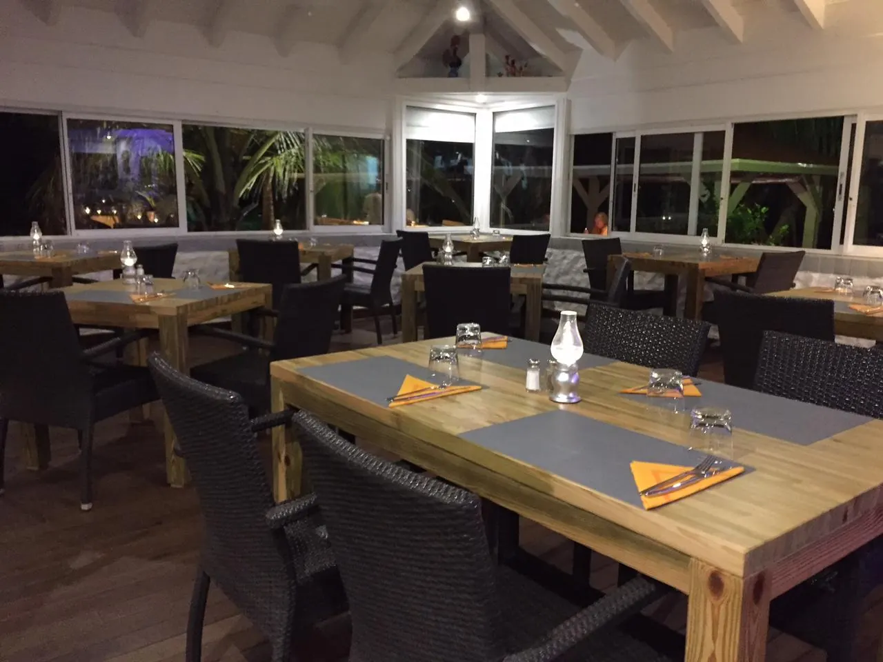 Salle intérieure de Mezza Luna avec tables en bois et grandes baies vitrées
