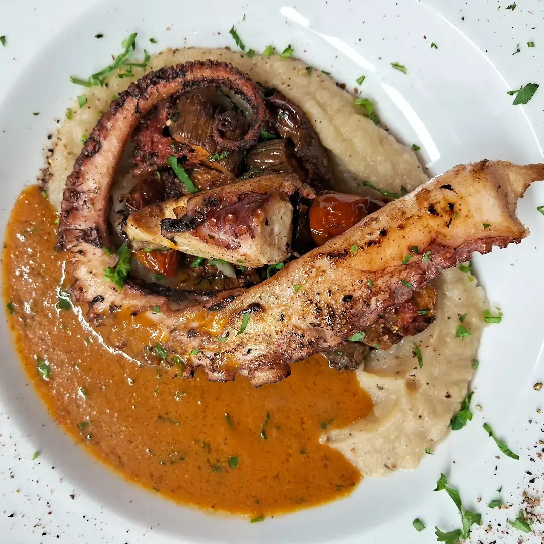 Poulpe grillé servi avec sauce crémeuse et pommes de terre à Mezza Luna