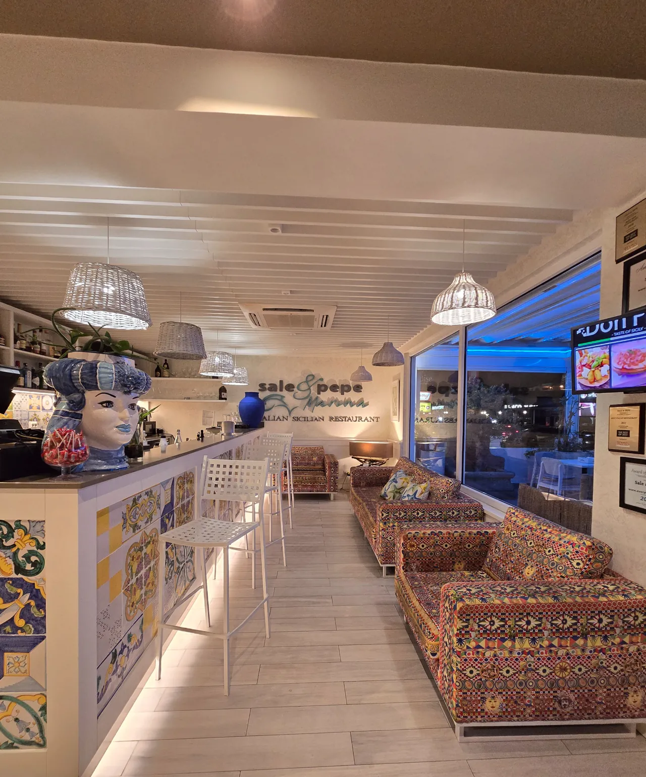 Bar intérieur de Sale & Pepe avec tête Testa di Moro, carreaux siciliens et banquettes colorées