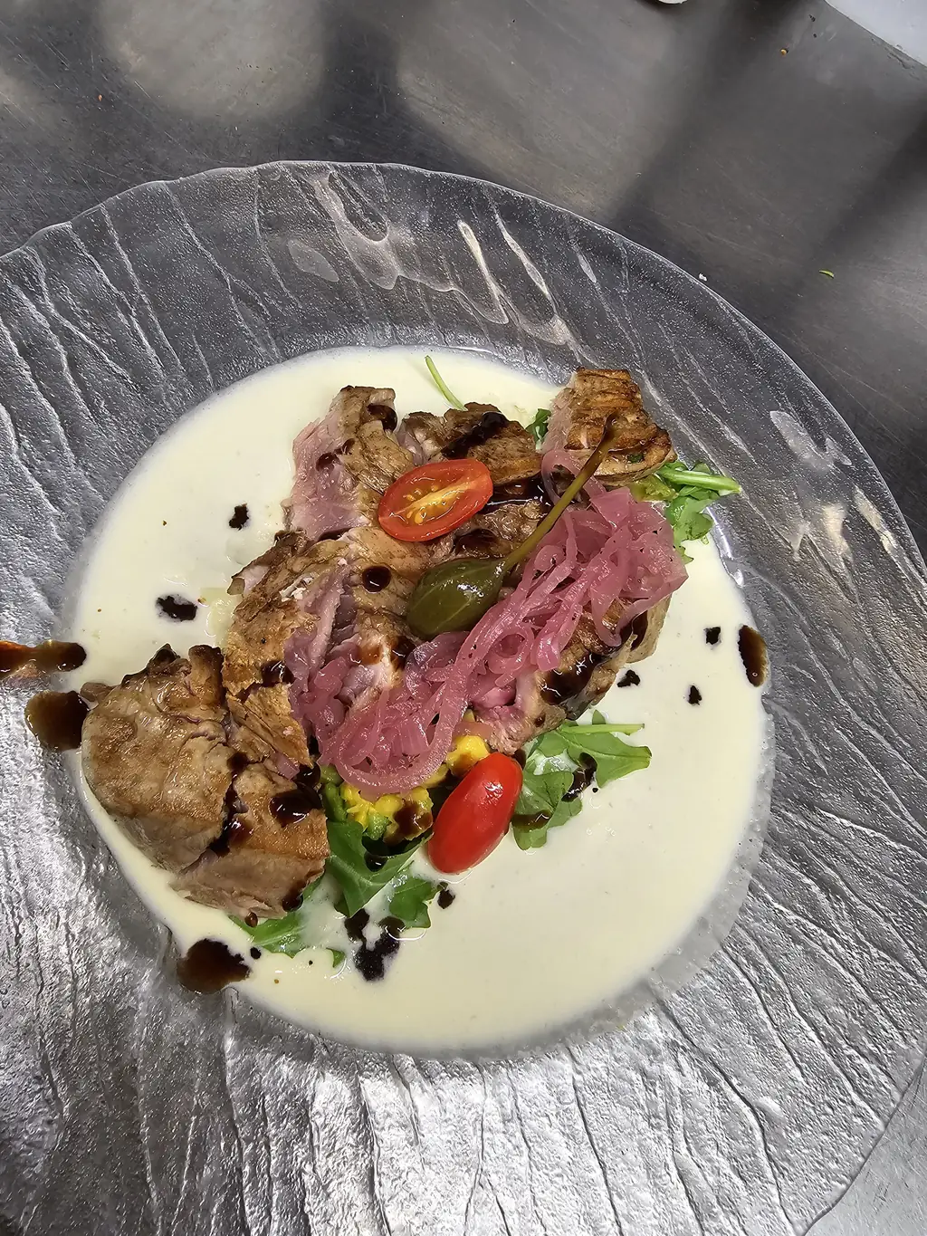 Plat signature italien de Sale & Pepe : viande sauce crémeuse, oignons rouges et roquette