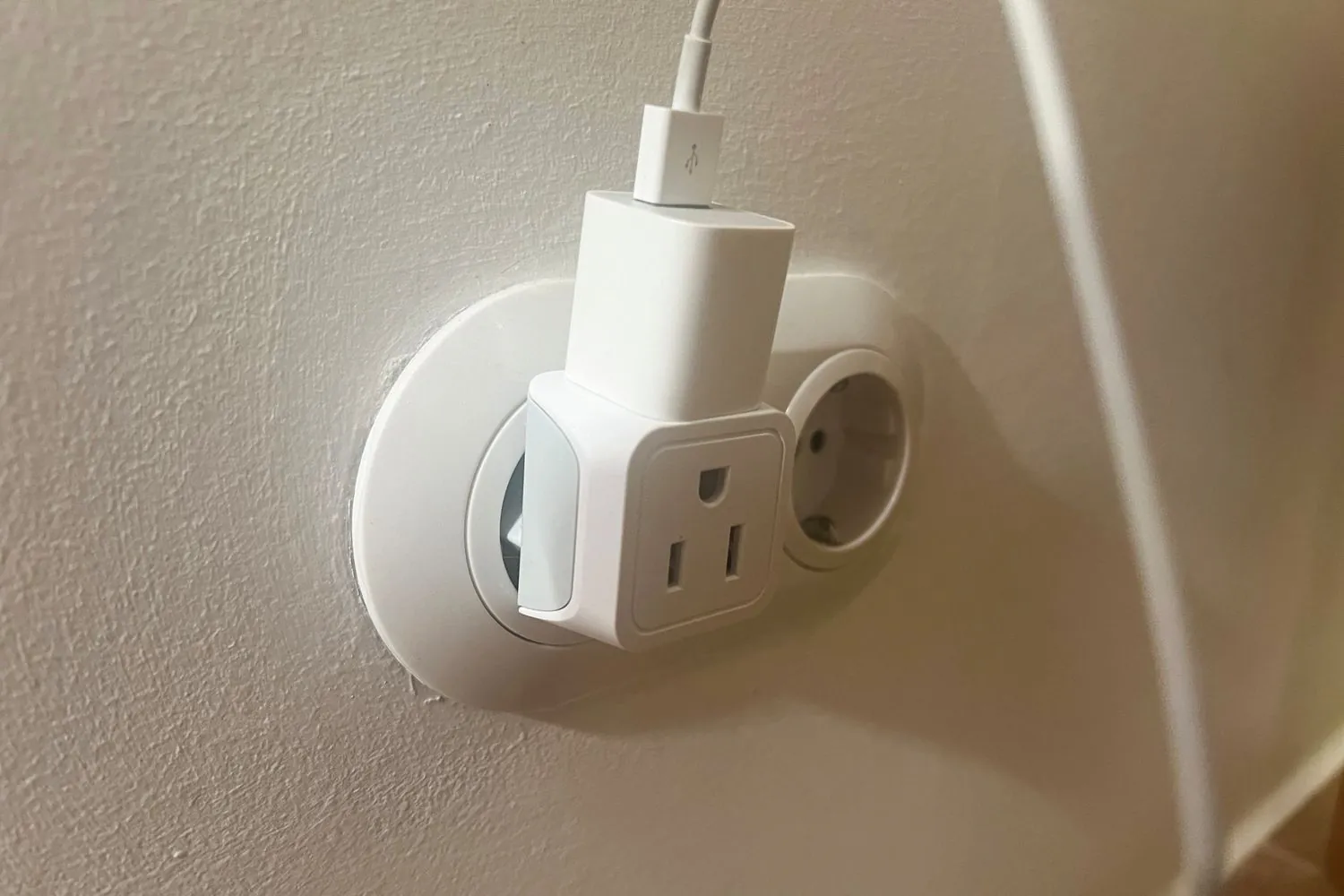 Adaptateur pour fiche américaine branché dans une prise européenne, avec un chargeur de téléphone