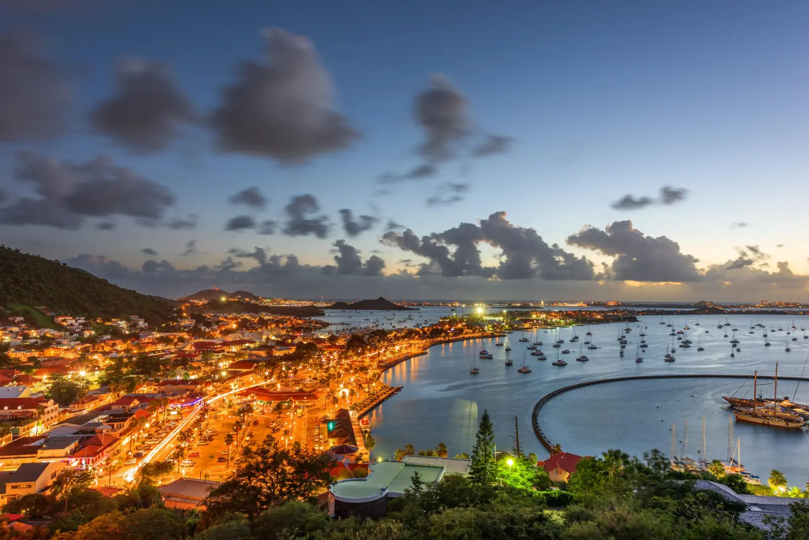 Marigot à la tombée de la nuit, lumières de la ville et voiliers dans la baie