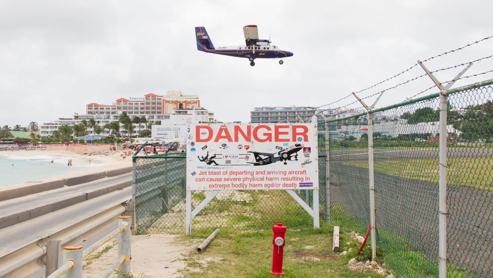 Panneau « Danger » sur le souffle des avions au bout de la piste, à Maho Beach, avec un avion à l'atterrissage