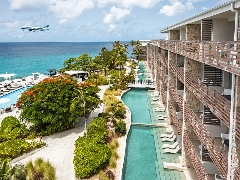 Le Sonesta Ocean Point, sa piscine en longueur au pied des suites et un avion en approche au-dessus de la mer