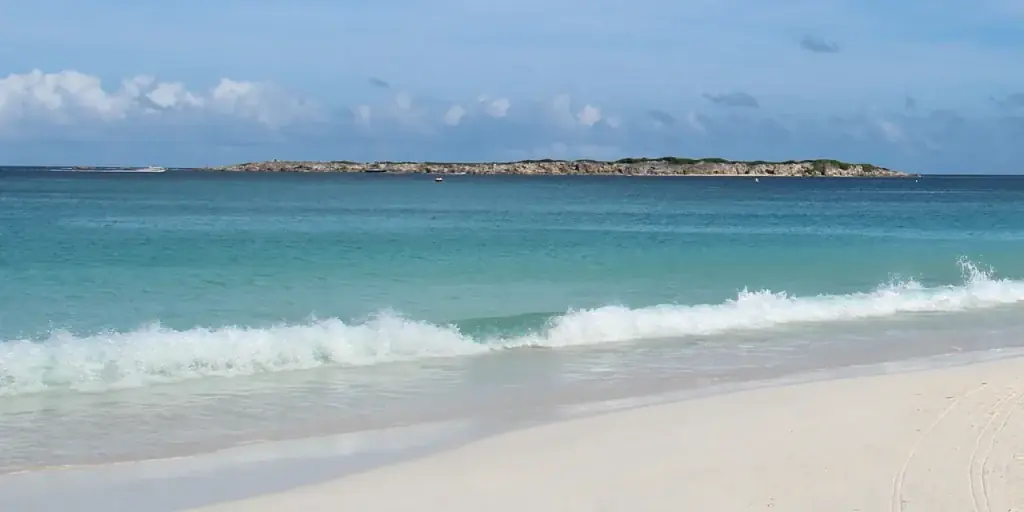 Vague sur sable blanc de la Baie Orientale avec Caye Verte en arrière-plan