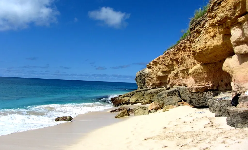 Crique de Cupecoy Beach avec sable clair, mer turquoise et falaises de grès ocre