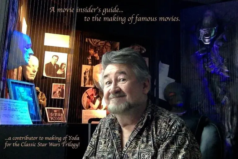 Nick Maley devant des moulages de visages et des photos de tournage